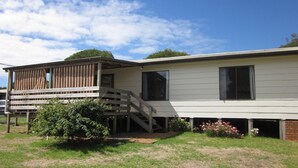 A two-story house with a wooden deck and a small porch. - Beachcomber Bliss the perfect family beach house. (SMITHS BEACH)