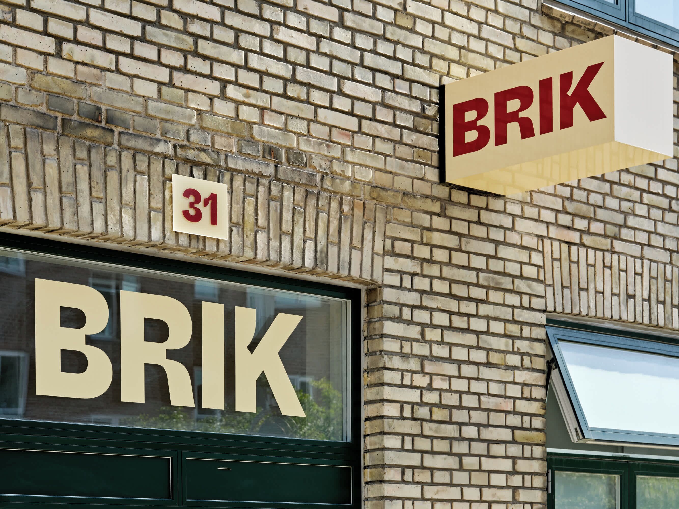 Eine Gebäudefassade, auf deren Fenster der Schriftzug 'BRIK' deutlich sichtbar ist und ein Schild darüber angebracht wurde.
