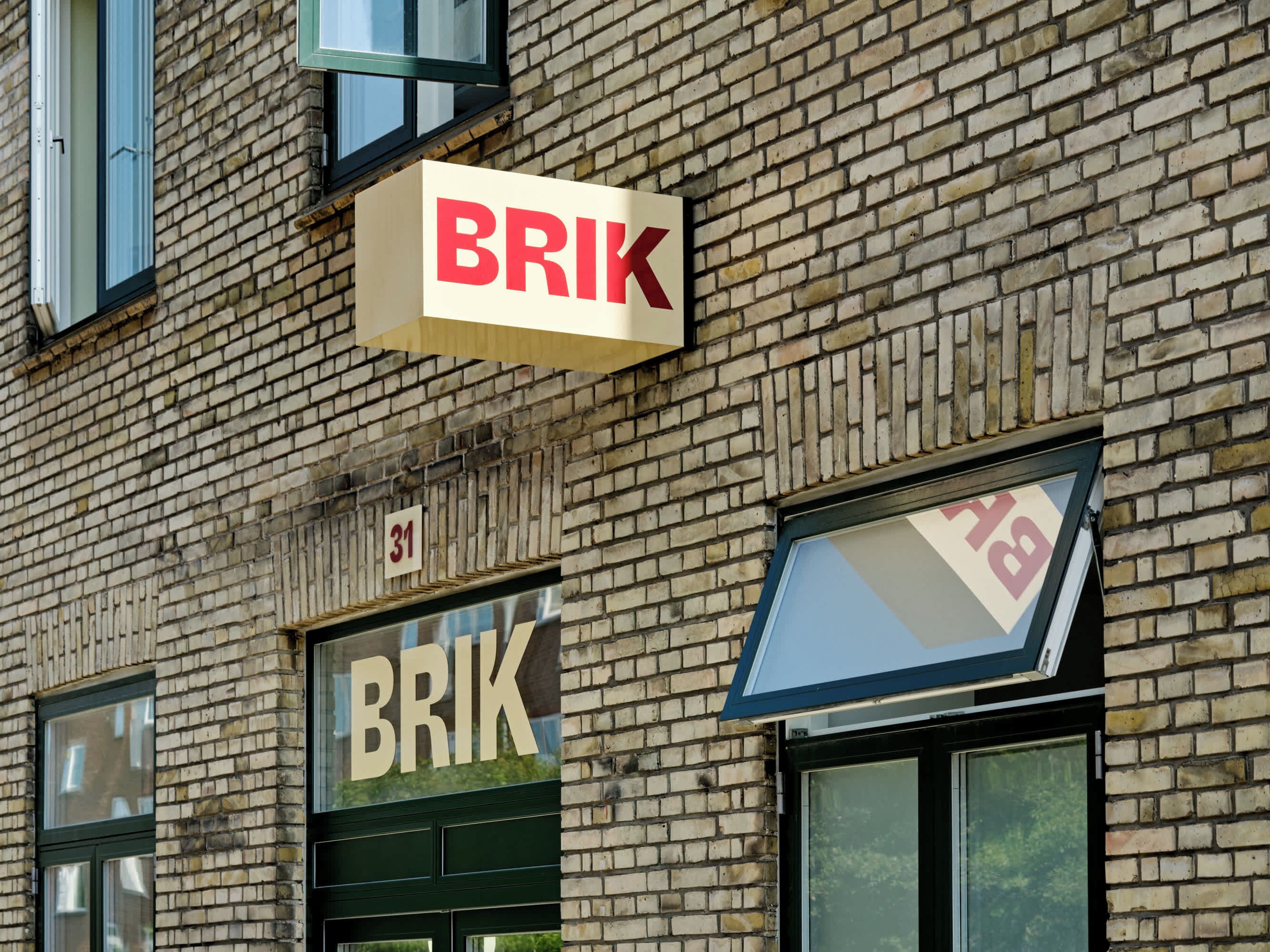 Un edificio in mattoni con un cartello che riporta "BRIK" e una finestra con il numero "31".