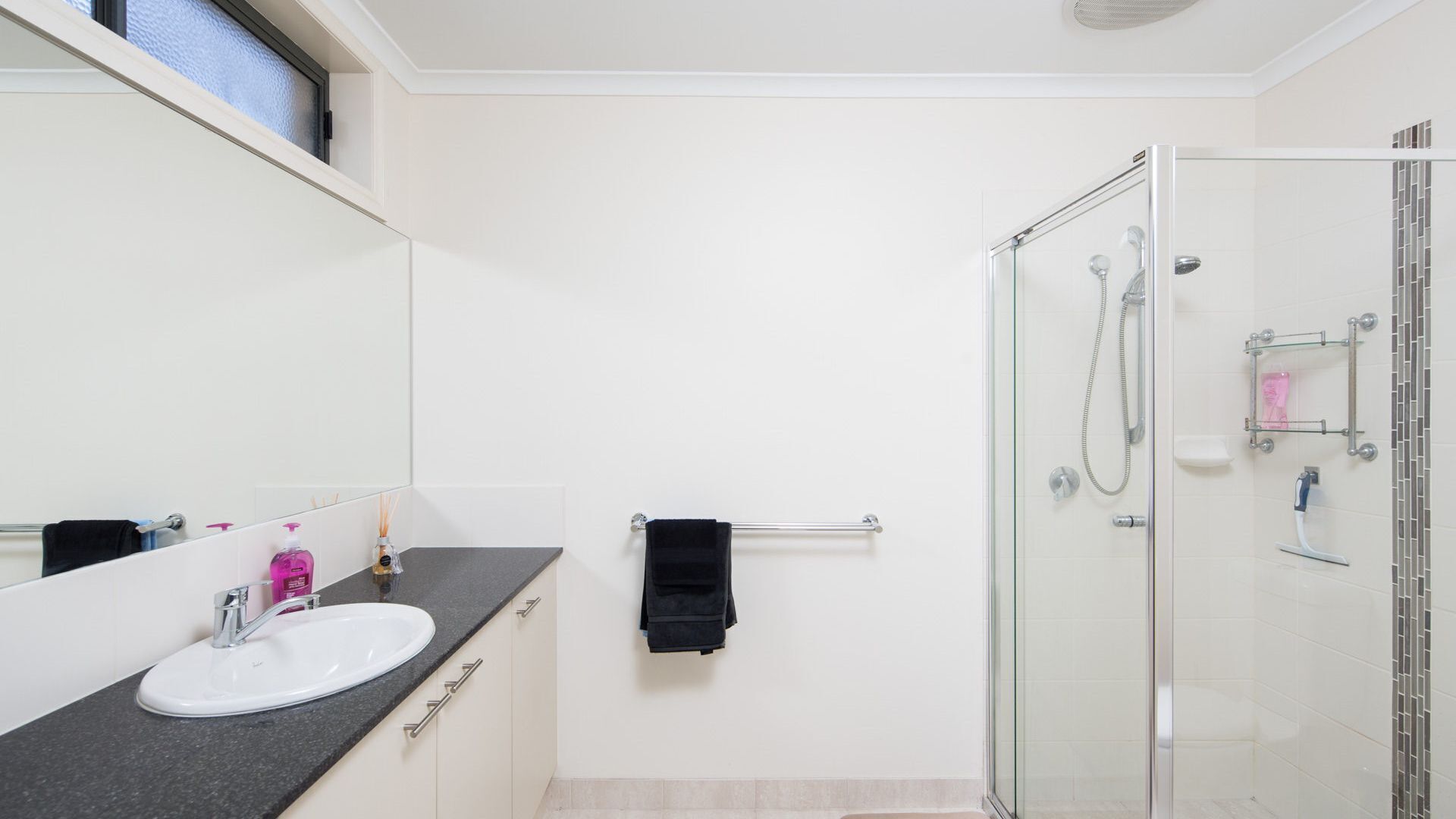 Une salle de bain moderne avec une douche à parois de verre, un lavabo blanc et un grand miroir.