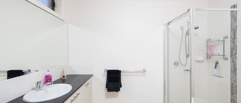 Une salle de bain moderne avec une douche à parois de verre, un lavabo blanc et un grand miroir.