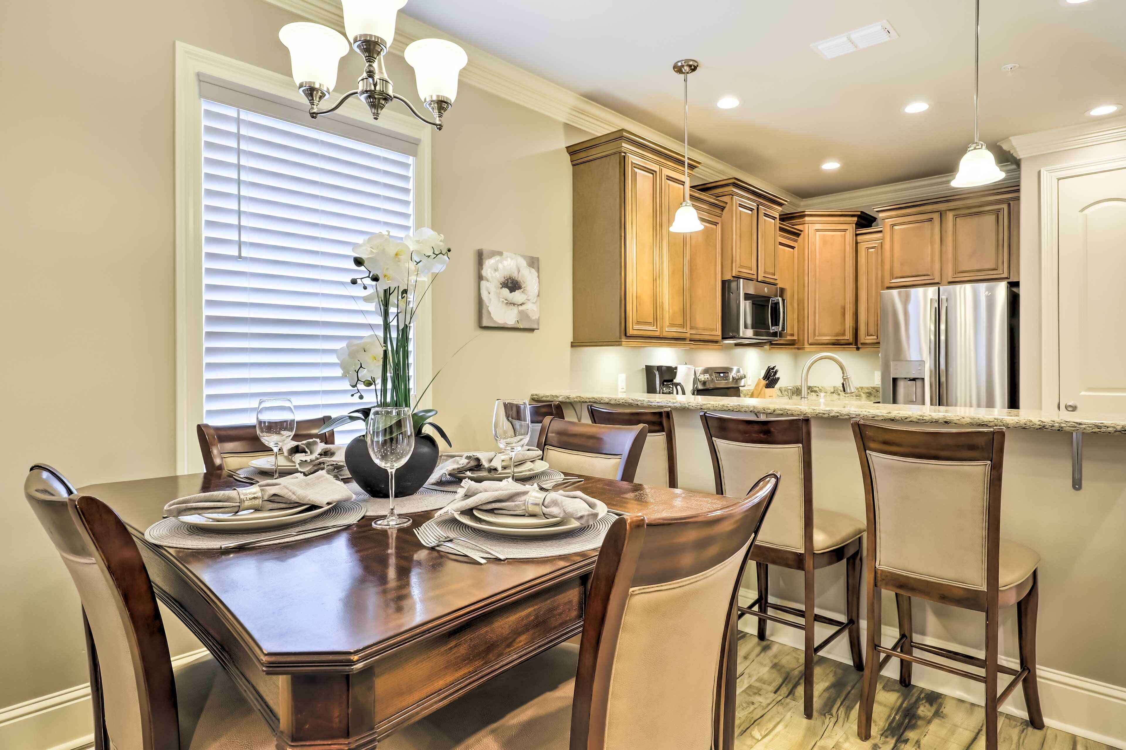 A dining area with a wooden table set for four, surrounded by chairs.