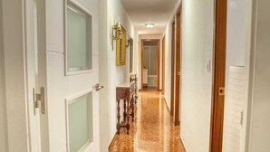 Un couloir avec des portes blanches, un meuble en bois et un miroir accroché au mur.