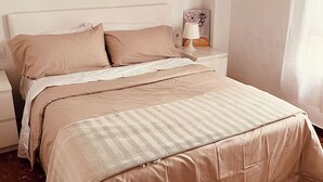 Une chambre à coucher avec un lit, des oreillers, une table de chevet, une lampe et une œuvre d’art murale.