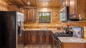 Una cocina con armarios de madera, un refrigerador de acero inoxidable, un fregadero y una estufa.