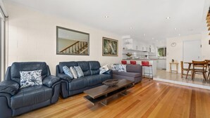 Ein modernes Wohnzimmer mit zwei Ledersofas, einem Holztisch und einer Küche im Hintergrund.