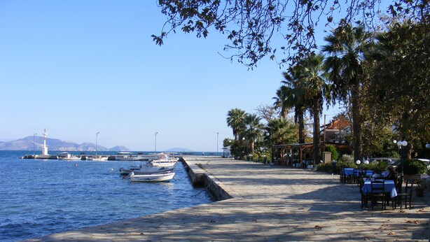A waterfront promenade with boats docked, a lighthouse in the background, and a restaurant area with outdoor seating. - Traditional villa with great views convenient for the beach, local area & sites (Argos)