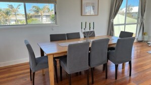 Un coin repas avec une table en bois, six chaises grises et un chandelier à neuf branches.