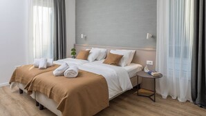 Et moderne hotelværelse med en stor seng, to puder, et natbord og en lille plante.