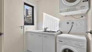 A compact laundry room with a Bosch washing machine, a sink, and a window.