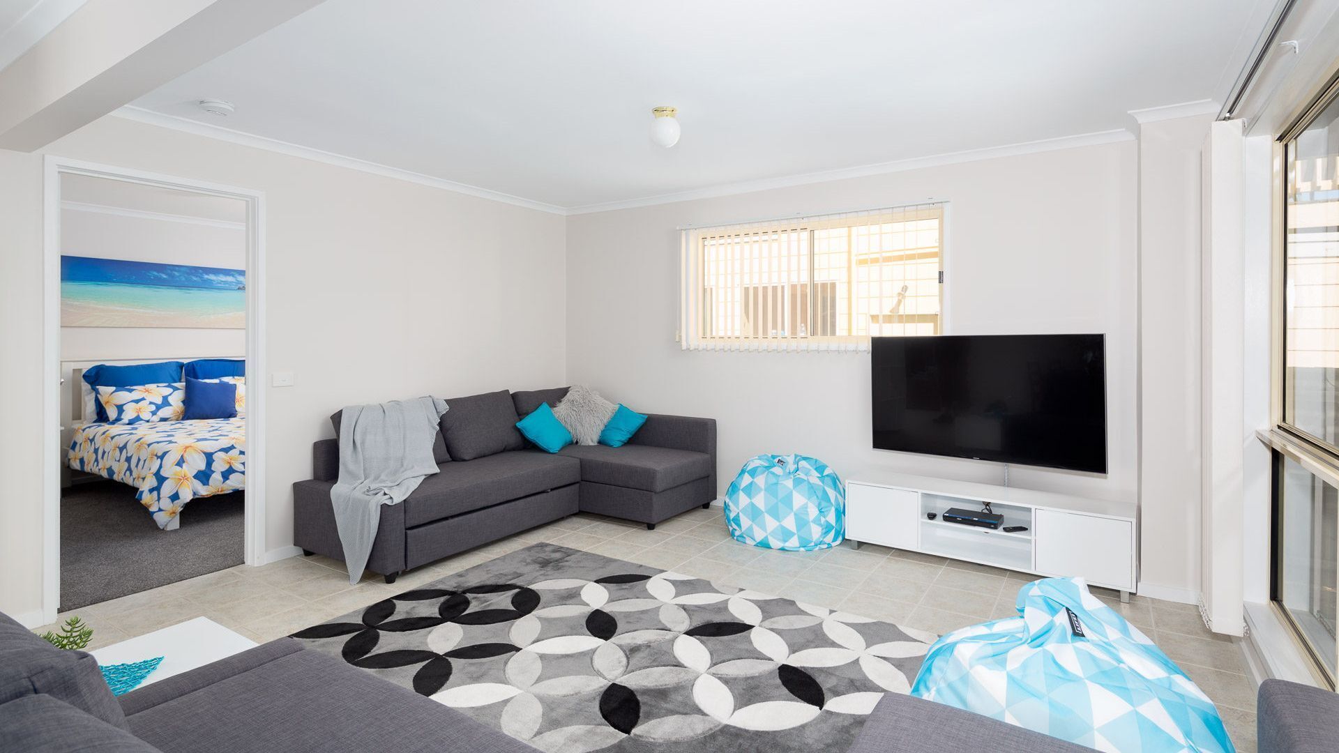 A modern living room with a grey sofa, a TV, and a patterned rug.