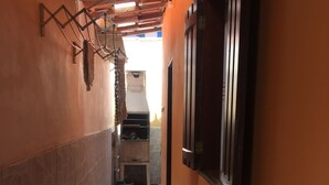Un couloir étroit doté d’un sol carrelé, d’un plafond en bois et d’un mur en briques sur un des côtés.