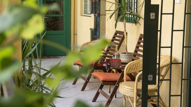 Eine Terrasse mit Korbmöbeln und einer grünen Tür.