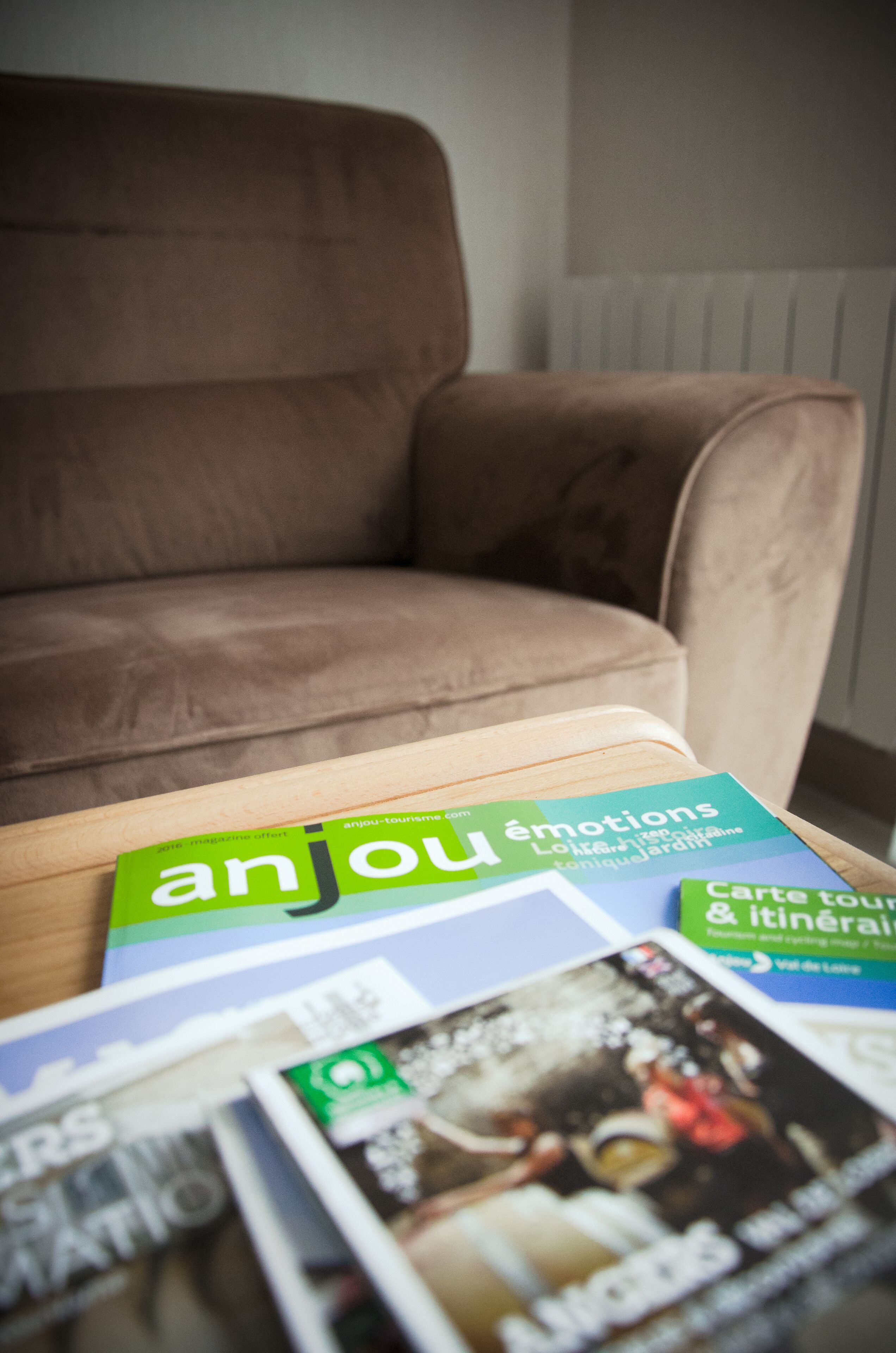 A brown armchair and a table with travel magazines.