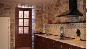 A kitchen with stone walls, a wooden door, and a tiled floor. - Rural house (full rental) El Empecinado for 23 people (Fuentelviejo)