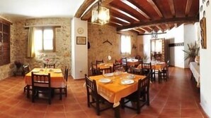 A rustic dining area with stone walls, wooden furniture, and a fireplace. - Rural house (full rental) El Empecinado for 23 people (Fuentelviejo)