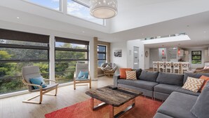 Amplia sala de estar con ventanas grandes, un comedor y una cocina.