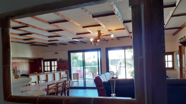 Uma sala de estar ampla com mesa e cadeiras de jantar, um sofá e um ventilador de teto.