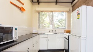 A kitchen with white cabinets, a microwave, a refrigerator, and a window with a view of trees. - Foreshore Escape Cowes #1 - short walk along the beach to Cowes main street (COWES)