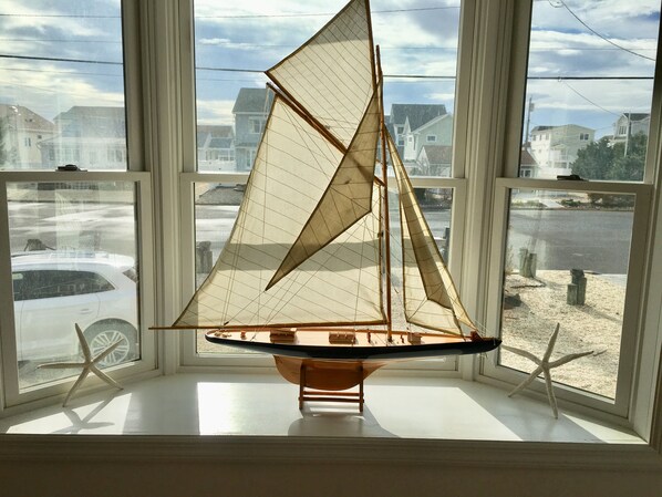 Enjoy a serene view of the surrounding neighborhood from this cozy windowsill, where a model sailboat gently unfurls its sails.