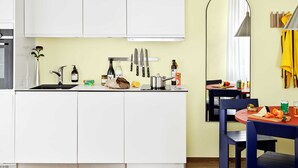 A compact kitchen with white cabinets, a sink, and a dining area with a table and chairs.