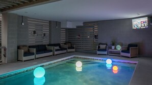Un'area piscina interna moderna, con posti a sedere e uno schermo di proiezione.