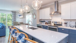 Una cucina moderna con un'ampia isola, luci a sospensione e vista sull'esterno.