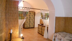 Un dormitorio con cama, mesita de noche, lámpara, armario y ventana con cortinas.