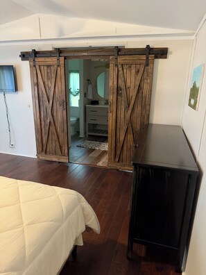 A bedroom with a bed, a dresser, and a sliding barn door closet.