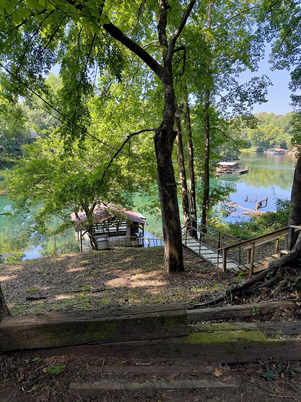 A lakeside view with a wooden deck leading to a gazebo-like structure.