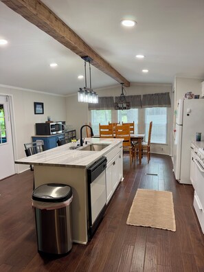 A modern kitchen with a central island, wooden flooring, and built-in appliances.