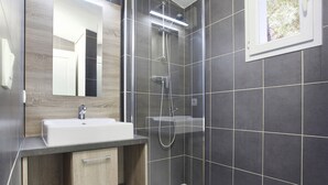 Un baño moderno con lavabo, espejo, ducha y ventana.
