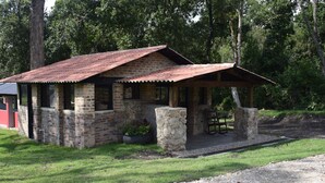 Un edificio rústico de piedra con techo de metal, un porche cubierto y un pequeño jardín.