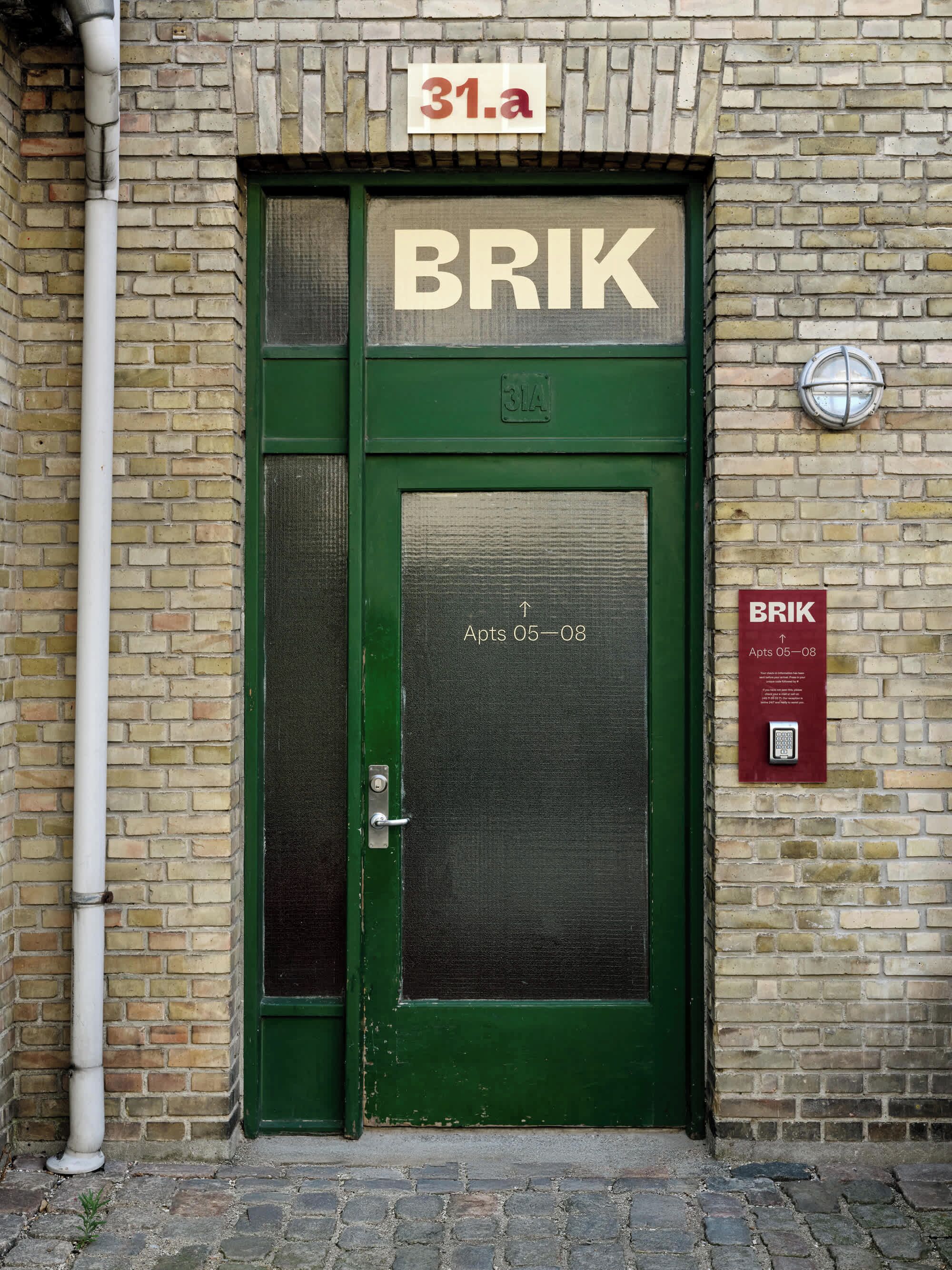 A green door with a sign reading "BRIK" and "Apts 05-08" indicating apartments 5 and 8.
