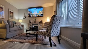 Ein Wohnzimmer mit Sofa, Sessel, Fernseher und Dekorationselementen.