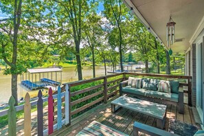 A wooden deck with a sofa and table, overlooking a lake with docked boats. - Updated Deck & Dock: Lakefront Home in Hot Springs (Hot Springs)