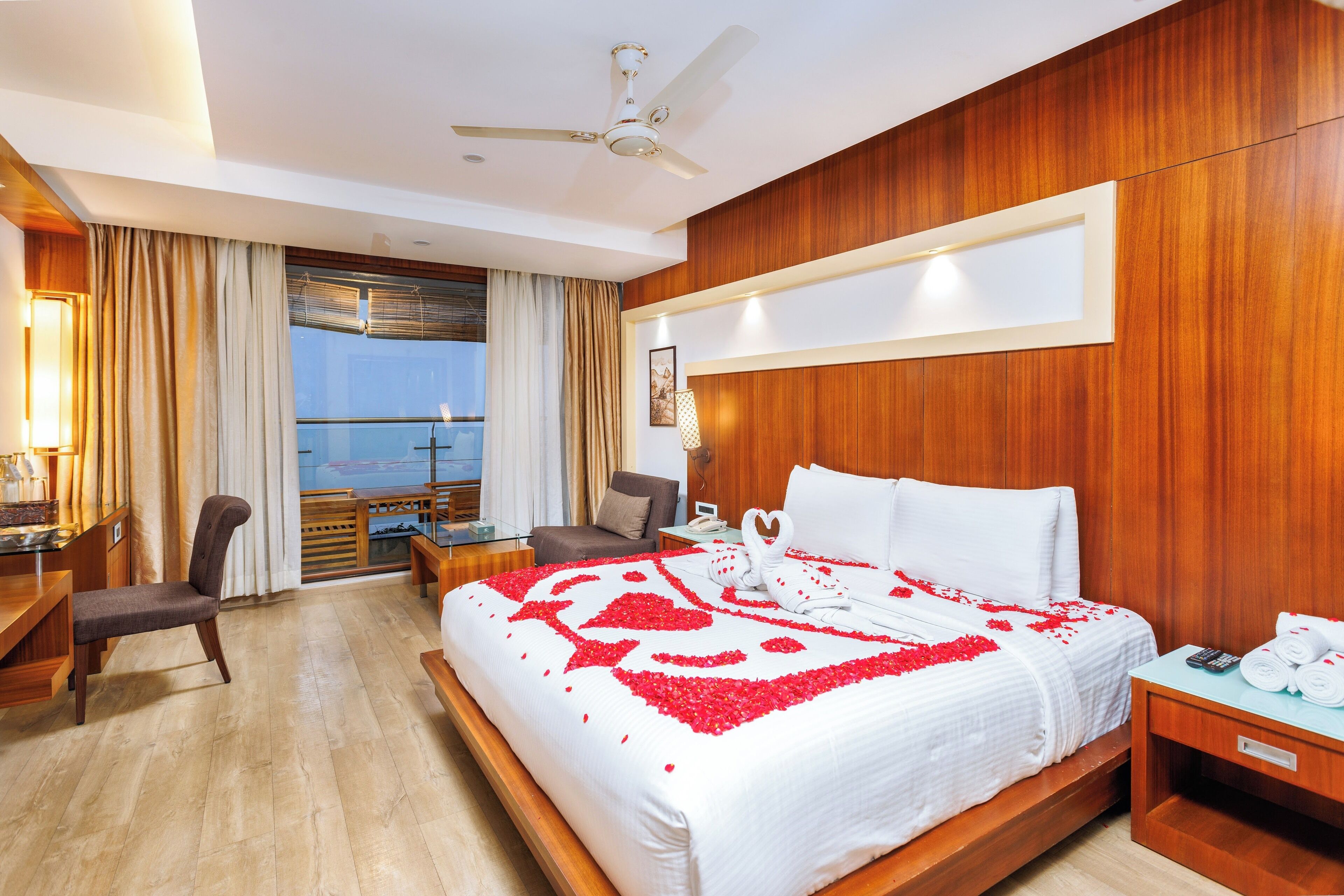Una habitación de hotel con cama, escritorio, silla, mesita de noche y vistas al exterior.