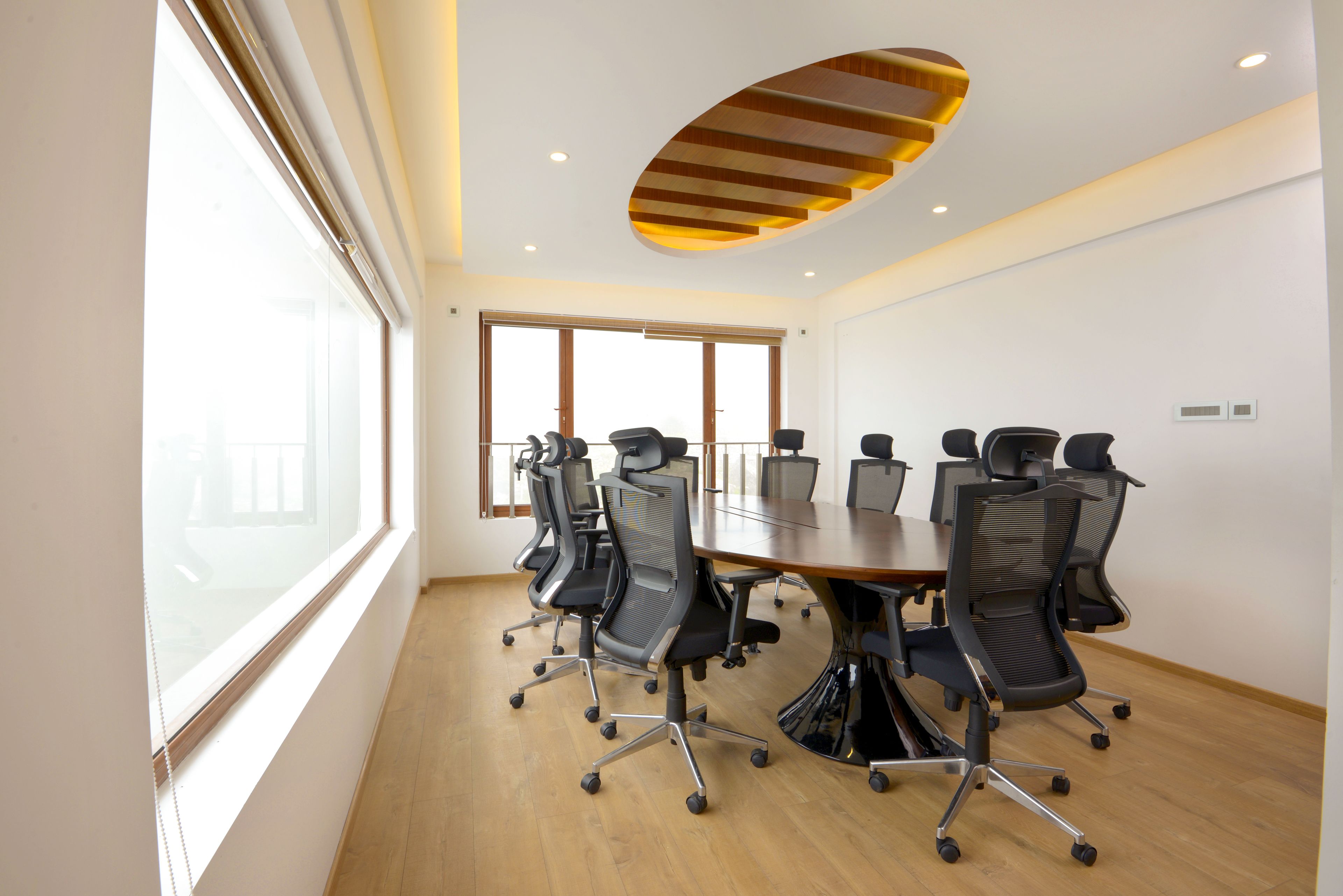A conference room with a large table, multiple chairs, and a modern ceiling design.