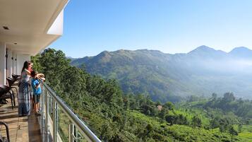 A balcony with a view of a lush valley and mountains.