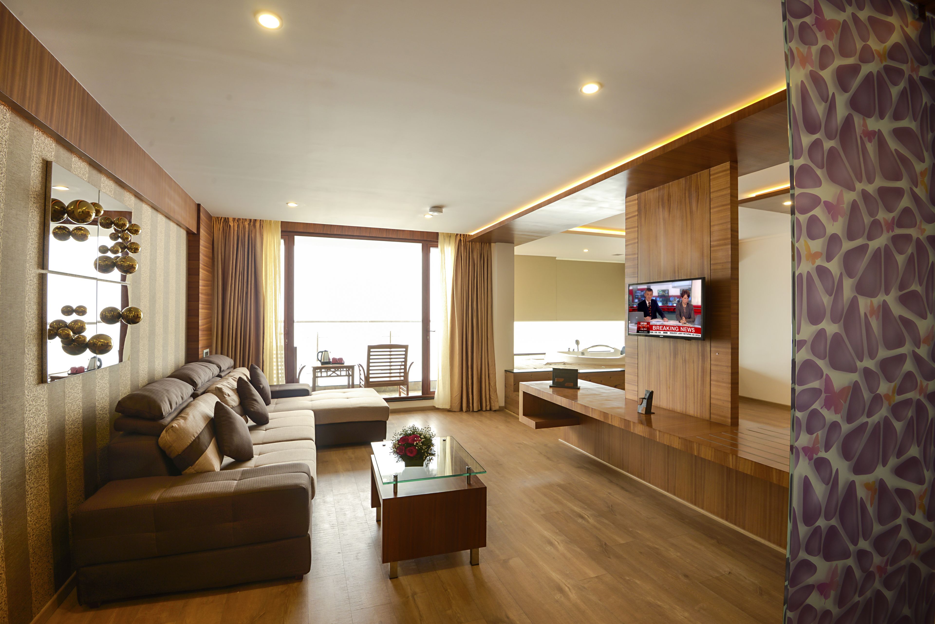 A modern living room with a sofa set, a glass coffee table, and a television.