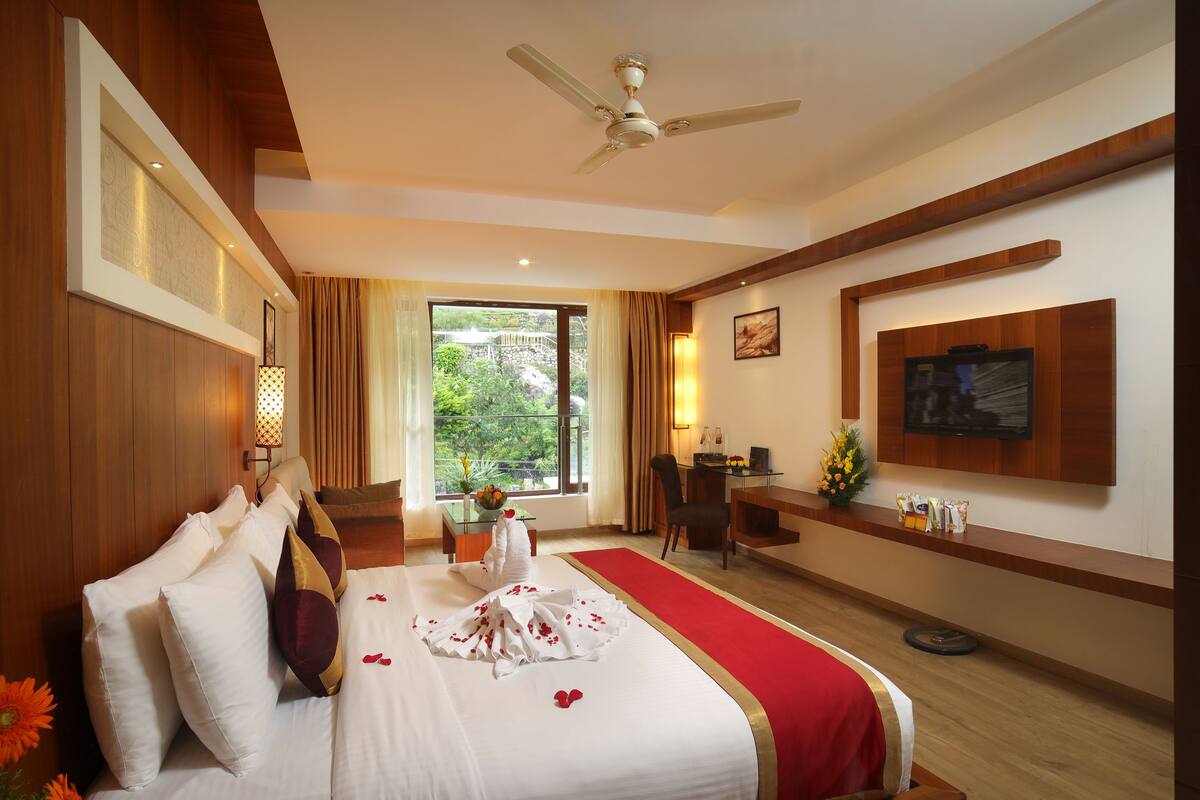 A hotel room with a bed, desk, and a large window.