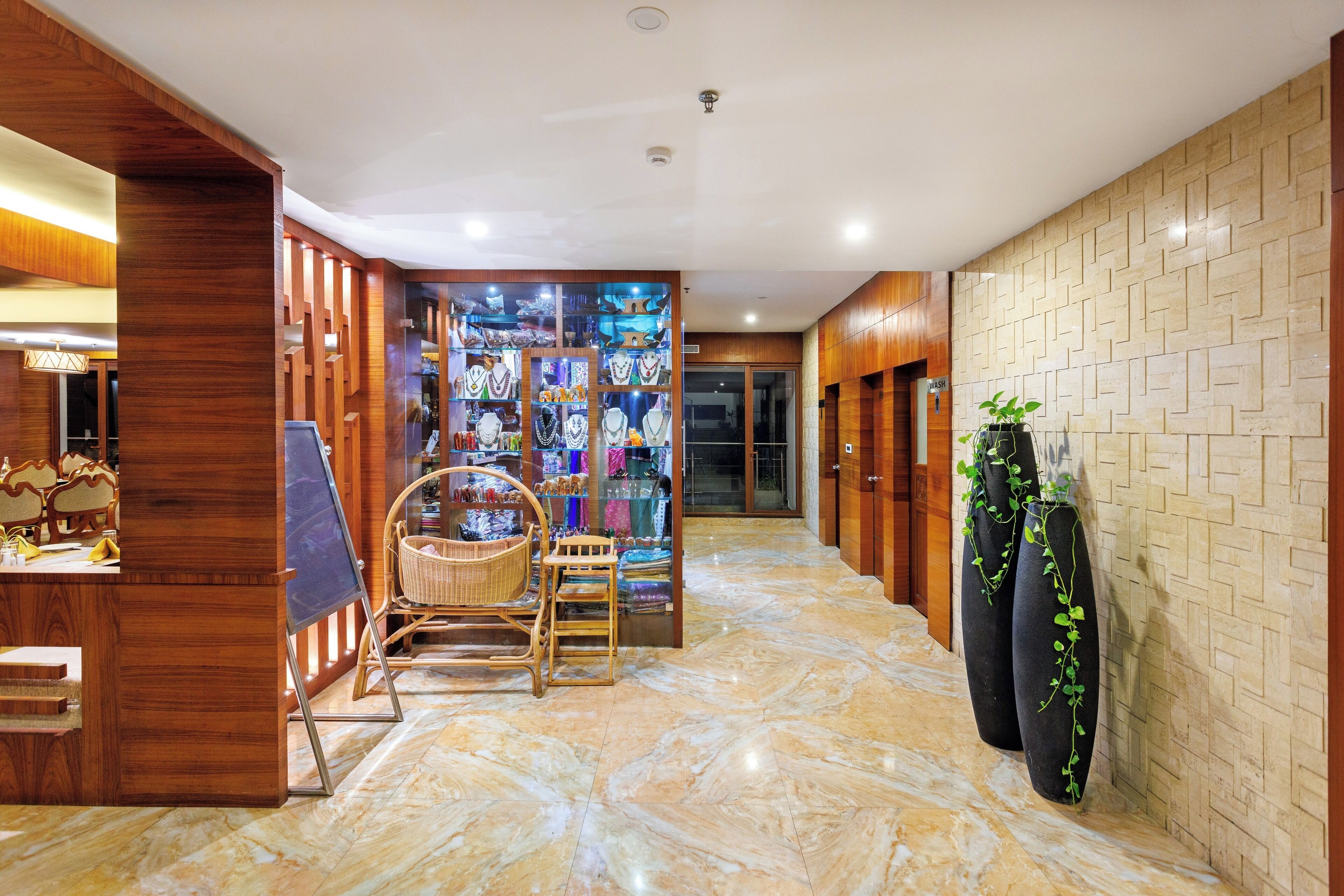 A hallway with wooden paneling, a reception desk, wicker chairs, and a display of various items.