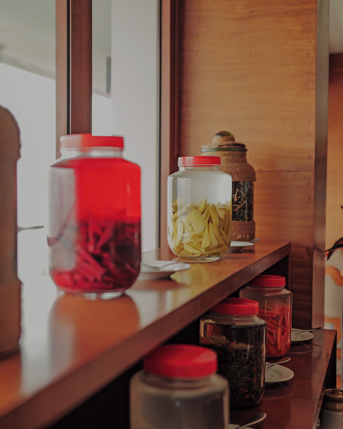 Un comptoir en bois sur lequel sont disposés divers bocaux en verre contenant différents aliments, probablement destinés au stockage ou à l’exposition.
