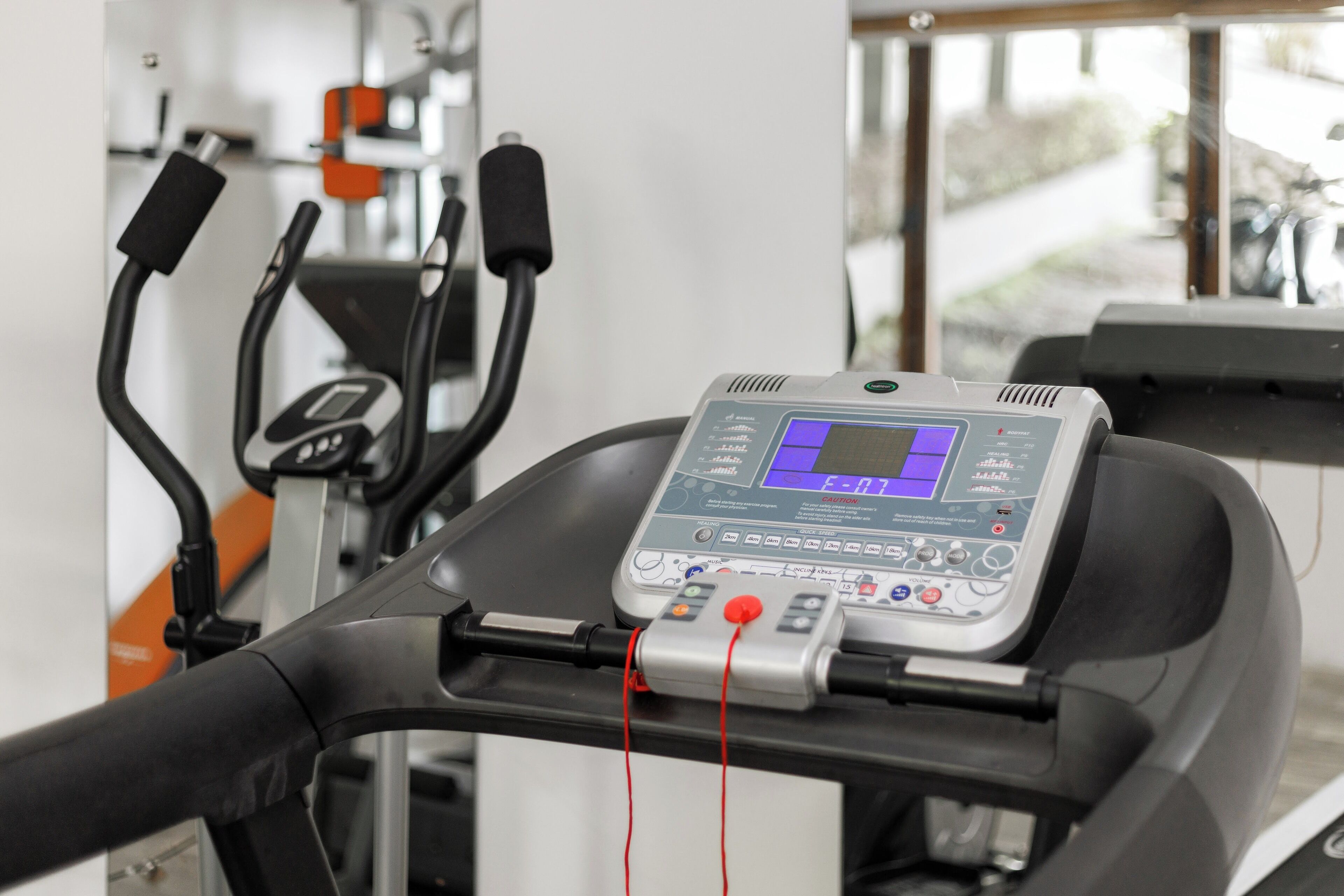 A stationary bike with a digital display and red cords.