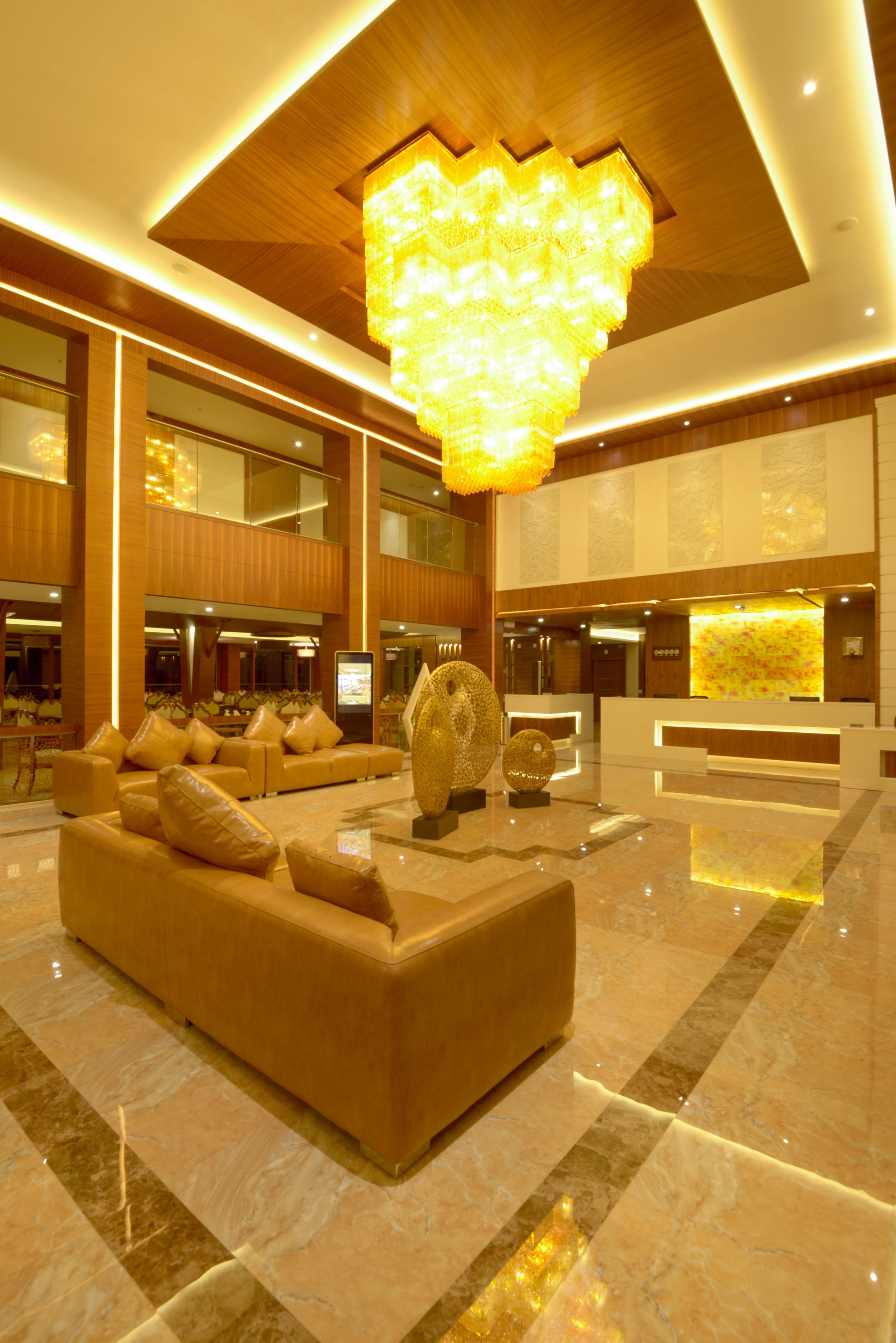 A spacious lobby with a large, illuminated chandelier, a reception desk, and a plush seating area.