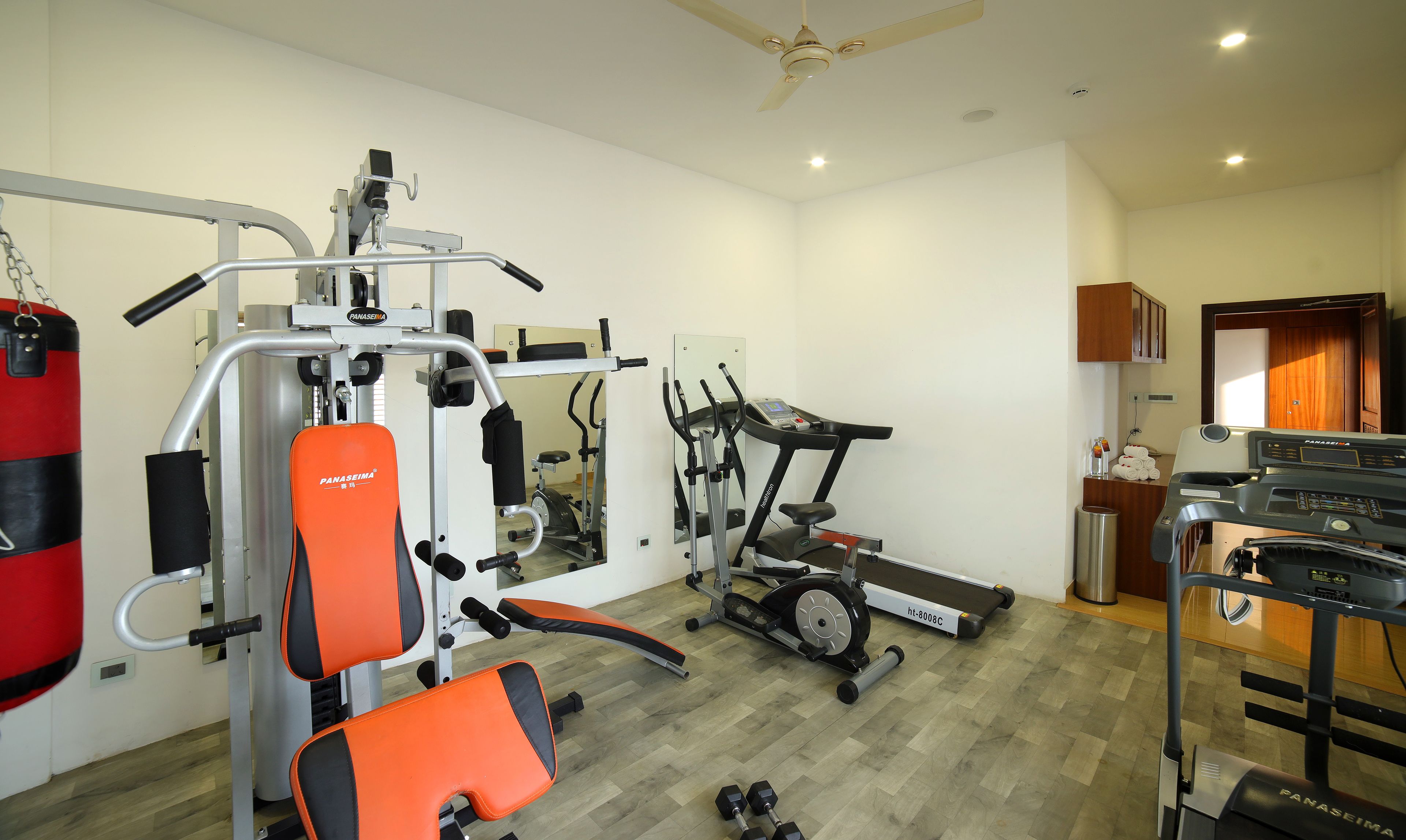 A home gym with a treadmill, weight bench, and various exercise equipment.