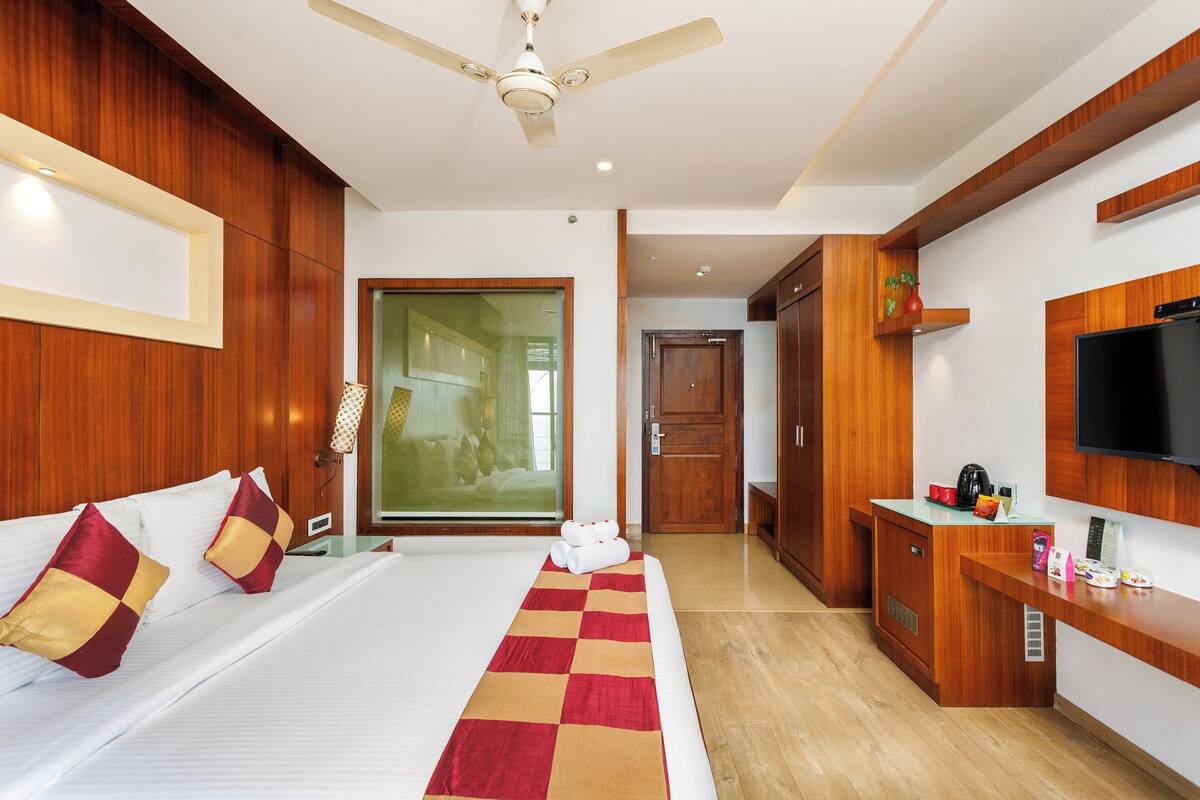 A hotel room with a bed, a desk, a television, and a ceiling fan.