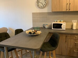A modern kitchen with a dining table, chairs, a microwave, and a clock on the wall. - Apartment/ flat - Ile Rousse (Ile Rousse)
