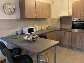 A modern kitchen with wooden cabinets, a microwave, a sink, and a stainless steel oven. - Apartment/ flat - Ile Rousse (Ile Rousse)