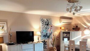 Un soggiorno con un divano, un tavolino, una TV e un quadro che raffigura una zebra sulla parete.